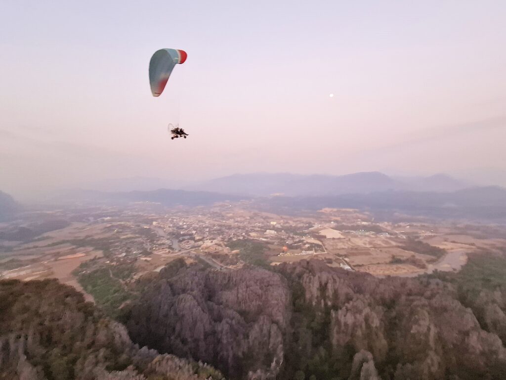 パラモーターでバンビエンの雄大な自然の山の上を飛んでいる写真