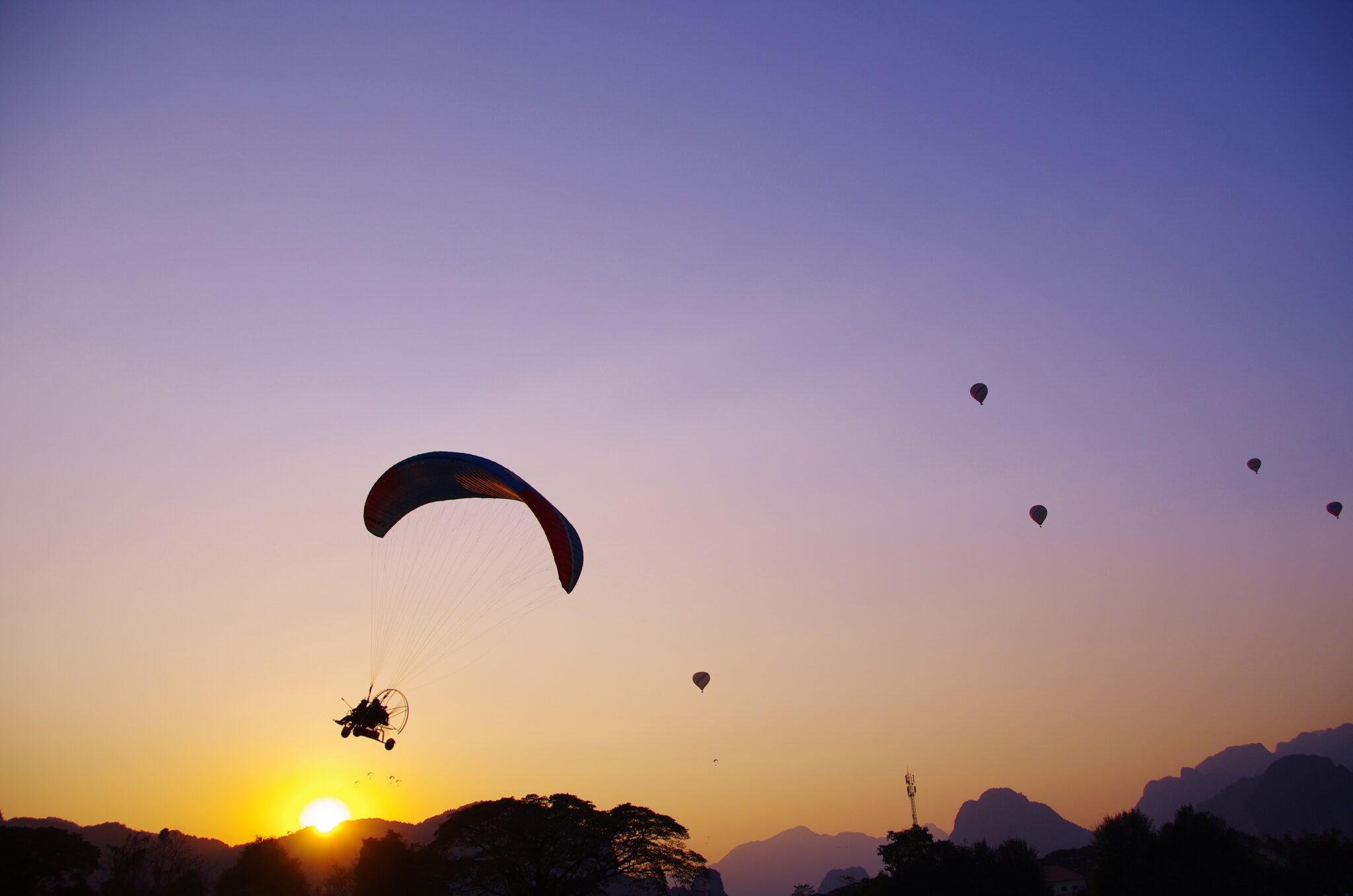 ラオスのバンヴィエンでの夕暮れのパラモーターの写真
