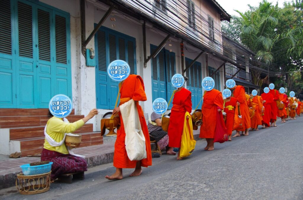 ラオスのルアンパバーンで、早朝の托鉢のときに一般の人たちが家の前を通る僧侶の鉢に食物を渡しているのを、多くの僧侶と一緒に撮った写真