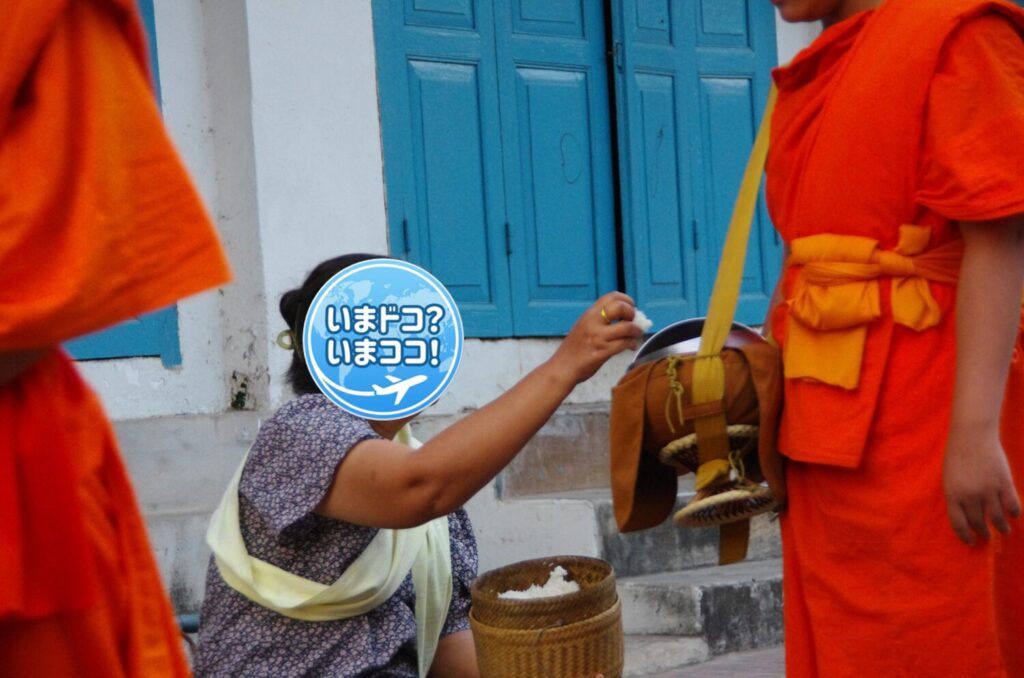 ラオスのルアンパバーンで、早朝の托鉢のときに一般の人たちが家の前を通る僧侶の鉢に食物を渡しているのを近くから撮った写真