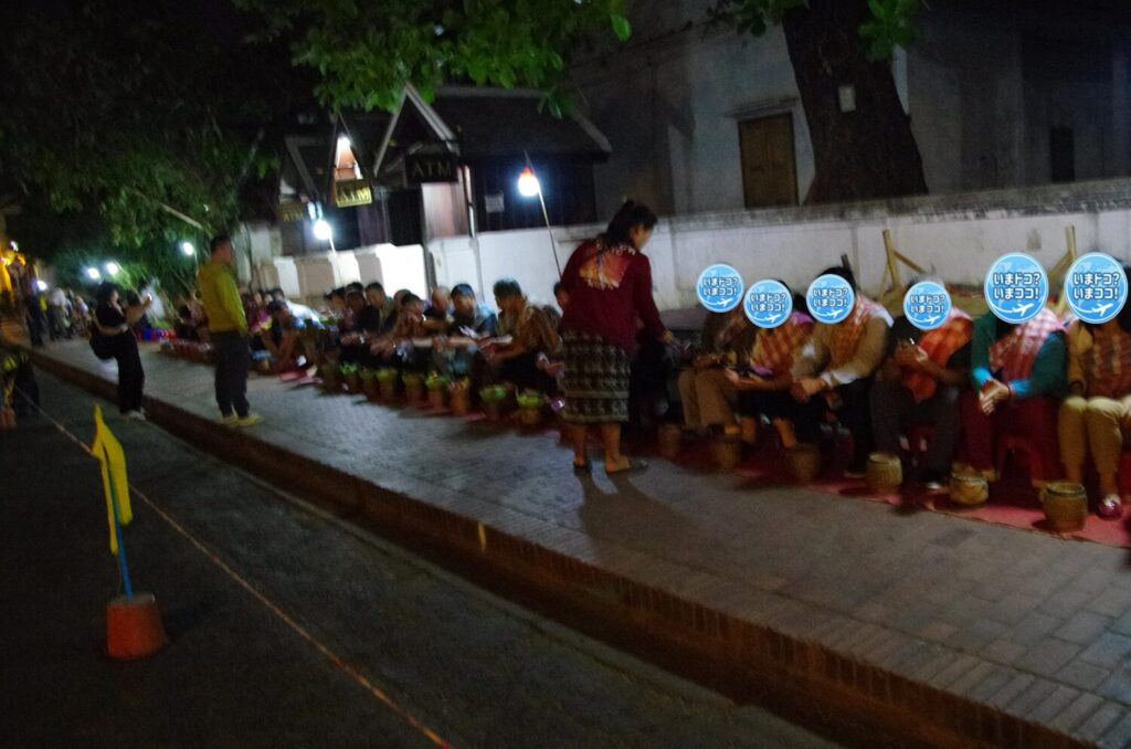 ラオスのルアンパバーンで、早朝の托鉢を体験する観光客が大勢並んで僧侶を待っているのを撮った写真