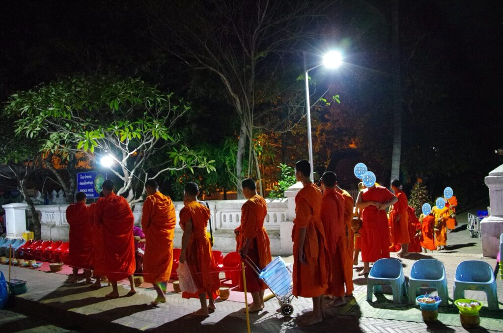 ラオスのルアンパバーンで、早朝の托鉢のために大勢の僧侶が寺院から出てきたときの写真