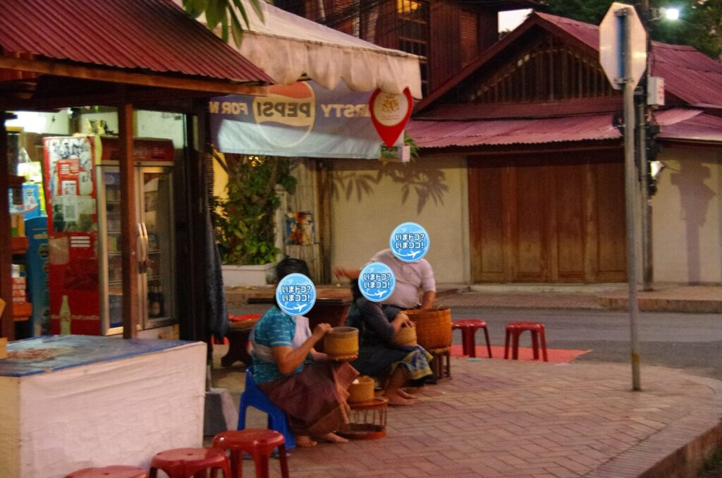 ラオスのルアンパバーンで、早朝の托鉢のときに一般の人たちが家の前を通る僧侶を待っているのを撮った写真