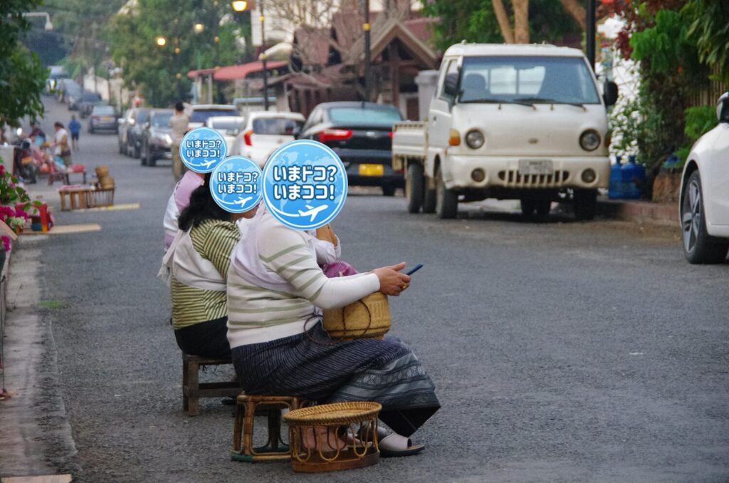 ラオスのルアンパバーンで、早朝の托鉢のときに一般の人たちが家の前を通る僧侶を待っているのを横から撮った写真