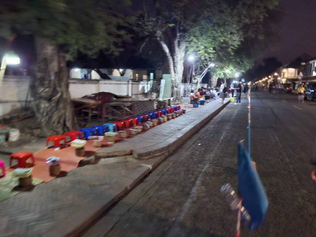 ラオスのルアンパバーンで、早朝の托鉢で、歩道と道路の間に貼られたロープの様子を撮った写真