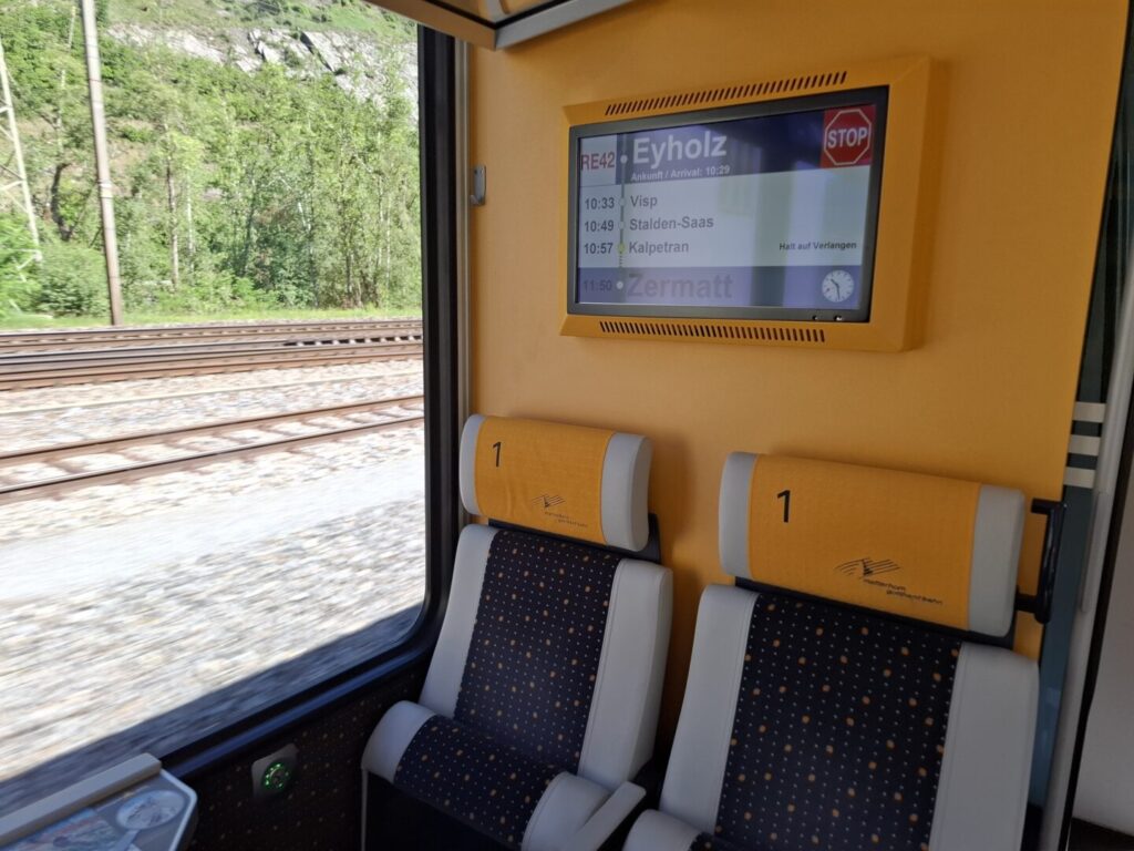 筆者が乗ったマッターホルン・ゴッタルド鉄道1等車内の椅子と行き先掲示板の写真