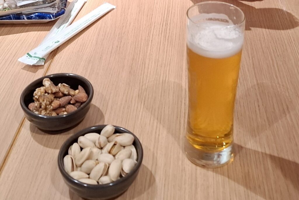 筆者が訪れた広島県福山市で宿泊したカンデオホテルズ福山でハッピーアワーで提供された生ビールと無料おつまみのナッツを撮った写真