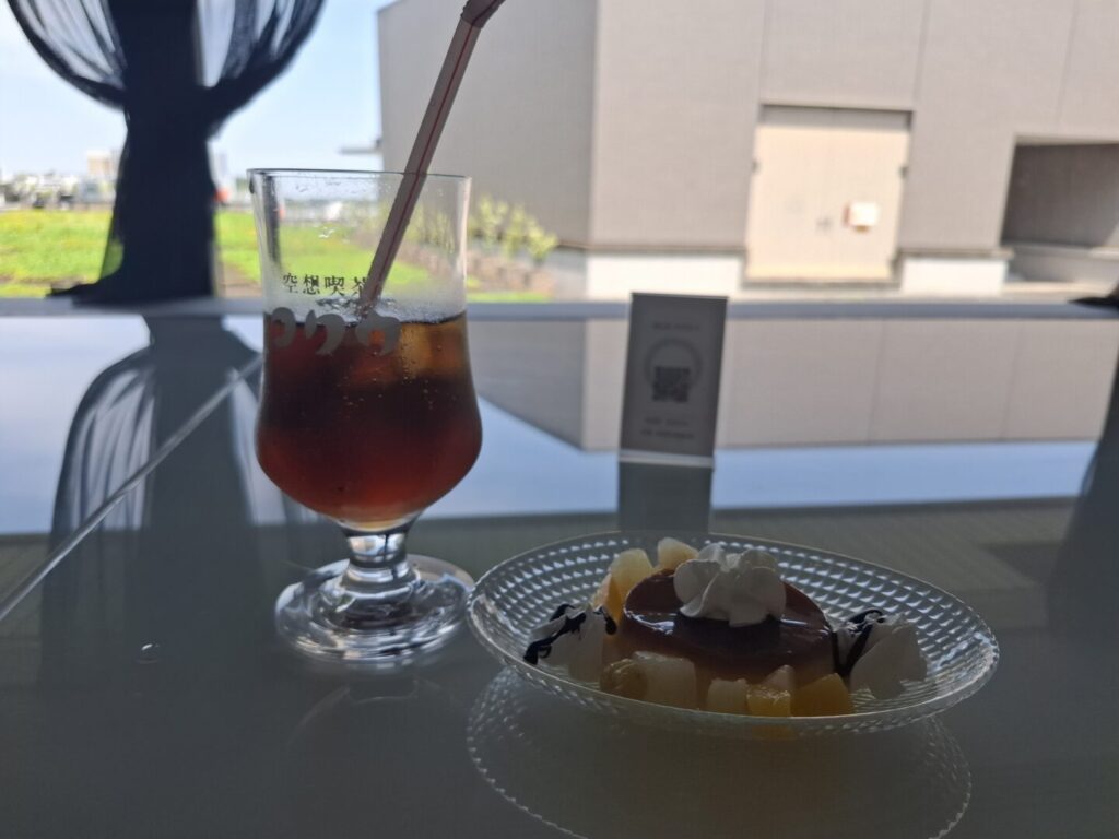 筆者が訪れた成田空港の第2ターミナルのラウンジKocooで提供されるプリンアラモードとクラフトコーラをとった写真