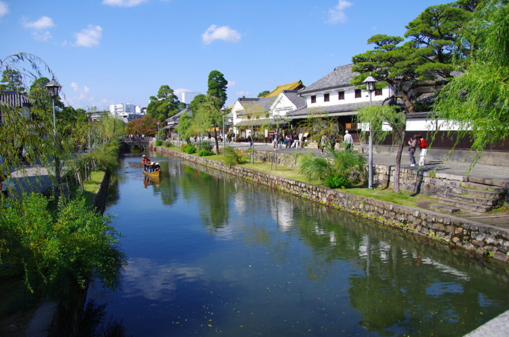 筆者が訪れた岡山県倉敷市の美観地区で、白壁の倉庫の前に流れる川を古い手漕ぎ船が進む様子を撮った写真