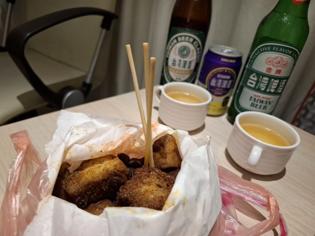 筆者が台湾の饒河街観光夜市の東山鴨頭屋台テイクアウトしてホテルに持ち帰った東山鴨頭料理をビールと一緒に撮った写真