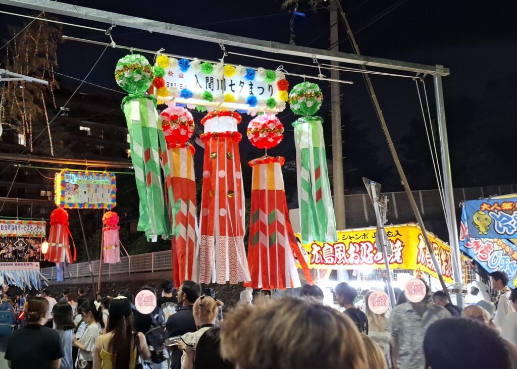 筆者が訪れた狭山市入間川七夕まつりで矢来飾りの構造がわかるような道の両側に柱が立っていてその間を棒で渡してあるのを撮った写真