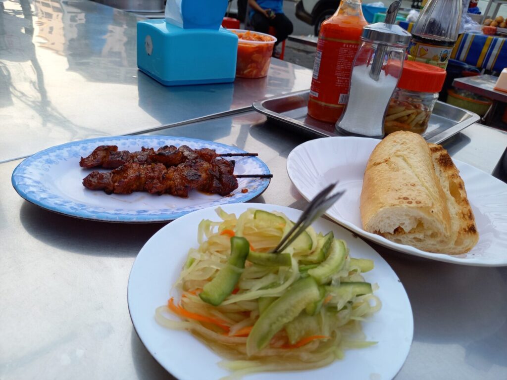 筆者がカンボジアのプノンペンでオルセーレストラン前の屋台で食べた串焼きとピクルスとパンを撮った写真