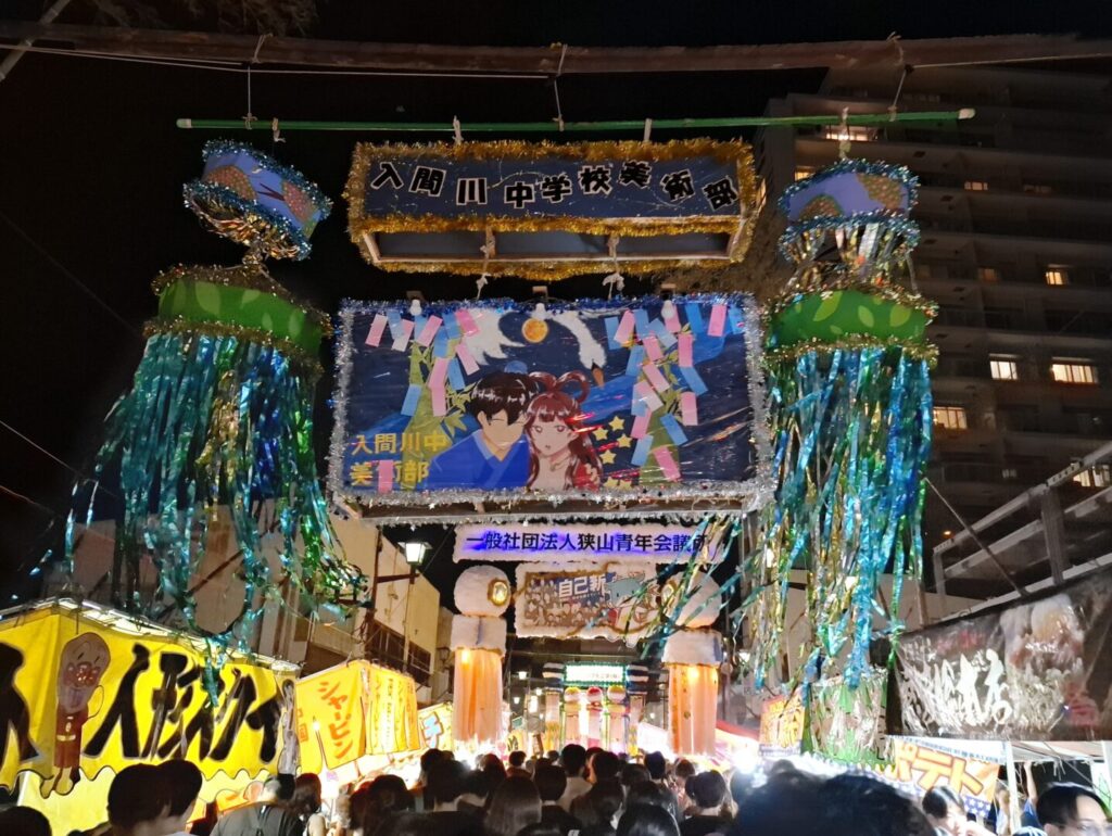 筆者が訪れた狭山市入間川七夕まつりで矢来飾りとその下に屋台がずっと続く様子を撮った写真
