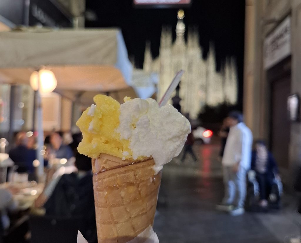 筆者が訪れたミラノのドゥオーモで向かいのカフェがあるエリアで買ったジェラートとライトアップされたドゥオーモを撮った写真